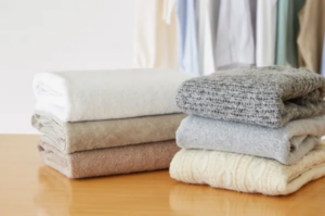 Folded blankets and knit throws stacked on a table